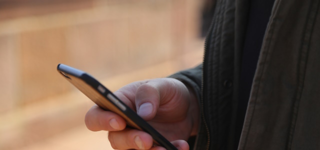 Symbolfoto Kontakt (Foto:Stadt HD) Seitliche Aufnahme einer Hand, die ein Smartphone hält.