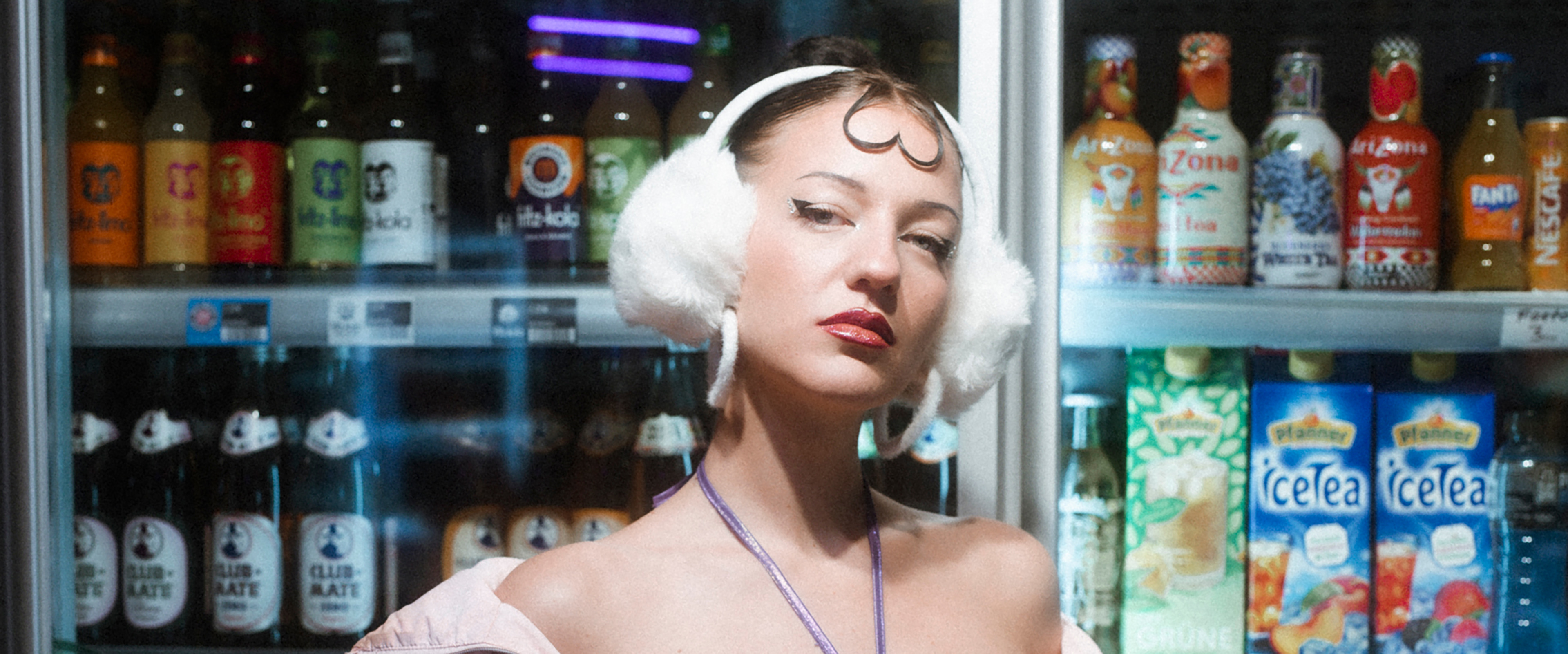 Frau mit Kopfhörern vor Getränkekühlschrank