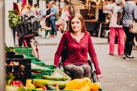 Eine Frau mit Rollstuhl schaut sich Gemüse auf dem Wochenmarkt an (Foto: Weiland)