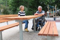 Eine Frau sitzt auf einer Bank an einem Tisch, ein Mann sitzt mit einem Rollstuhl am gleichen Tisch (Foto: Stadt Heidelberg)