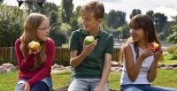 Zwei Mädchen und ein Junge sitzen nebeneinander und essen einen Apfel (Foto: Dorn)