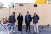 Architekt Weber, Hochbauamtsmitarbeiterin Moruno, Bürgermeister Odszuck und Hochbauamtsleiter Heußer stehen vor einem Holzmodul.