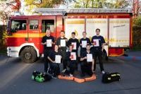 Die neu ausgebildeten Atemschutzgeräteträger zeigen stolz ihre Urkunde vor einem Feuerwehrfahrzeug zum bestandenen Lehrgang