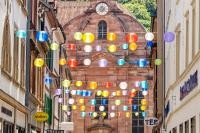 Die Seitengassen in der Altstadt halten viele inhabergeführten besondere Konzepten bereit. (Foto: Schwerdt/Heidelberg Marketing) Bunte Lampions hängen in der Neugasse zwischen den Hauswänden.