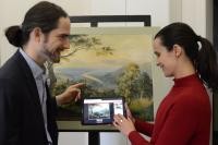 Zwei Menschen vor einem Gemälde mit Tablet