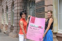 Zwei Frauen stehen vor dem Rathaus mit dem Werbeplakat für "perioHDe
