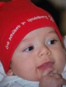 Ein Baby trägt eine rote Mütze mit der Aufschrift "Gut behütet in Heidelberg" und lächelt (Foto: Kristina Wetzel)