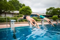 Zwei Jugendliche springen von einem Startblock in das Wasser