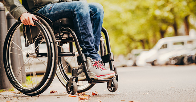 Ein Mensch mit Rollstuhl fährt über einen abgesenkten Bordstein (Foto Weiland/www.gesellschaftsbilder.de)