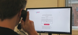 Employee with phone in front of computer screen 