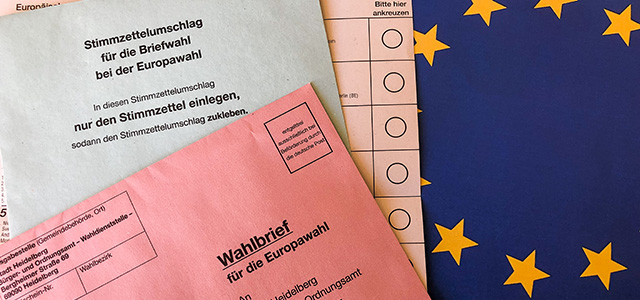 Wahlunterlagen der Europawahl mit EU-Flagge im Hintergrund.