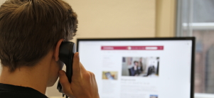 junger Mann von hinten fotografiert, der auf einen Bildschirm schaut und telefoniert