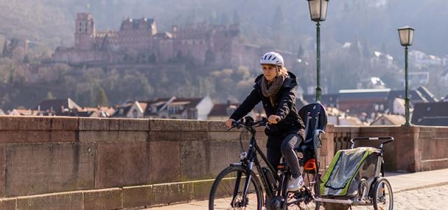 Frau fährt mit Rad und Fahrradanhänger über die Alte Brücke