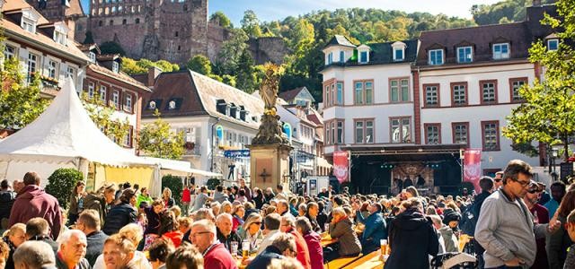 Menschen sitzen auf Biertischbänken auf dem Kornmarkt