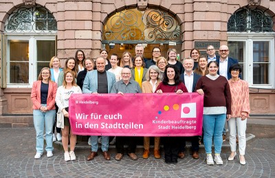 Die Kinderbeauftragten mit Oberbürgermeister Eckart Würzner (Reihe vorne, 3.v.l.) und Bürgermeisterin Stefanie Jansen (Reihe vorne, 1.v.r.). (Foto: Felix Bäcker) Gruppenfoto mit Banner "Wir für euch in den Stadtteilen"