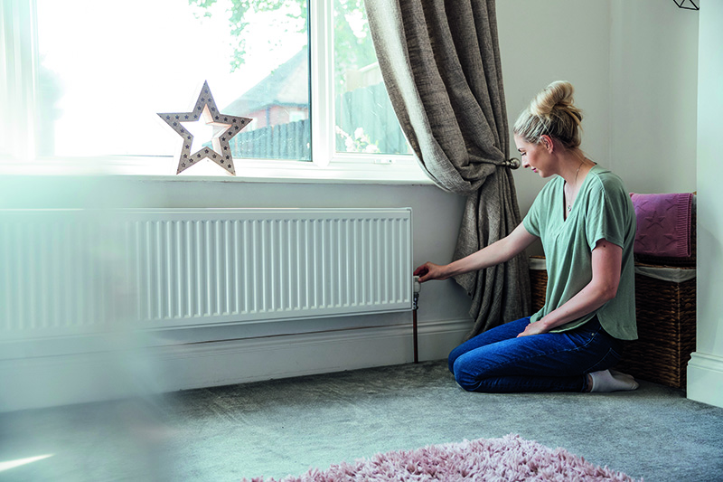 Frau dreht die Heizung runter
