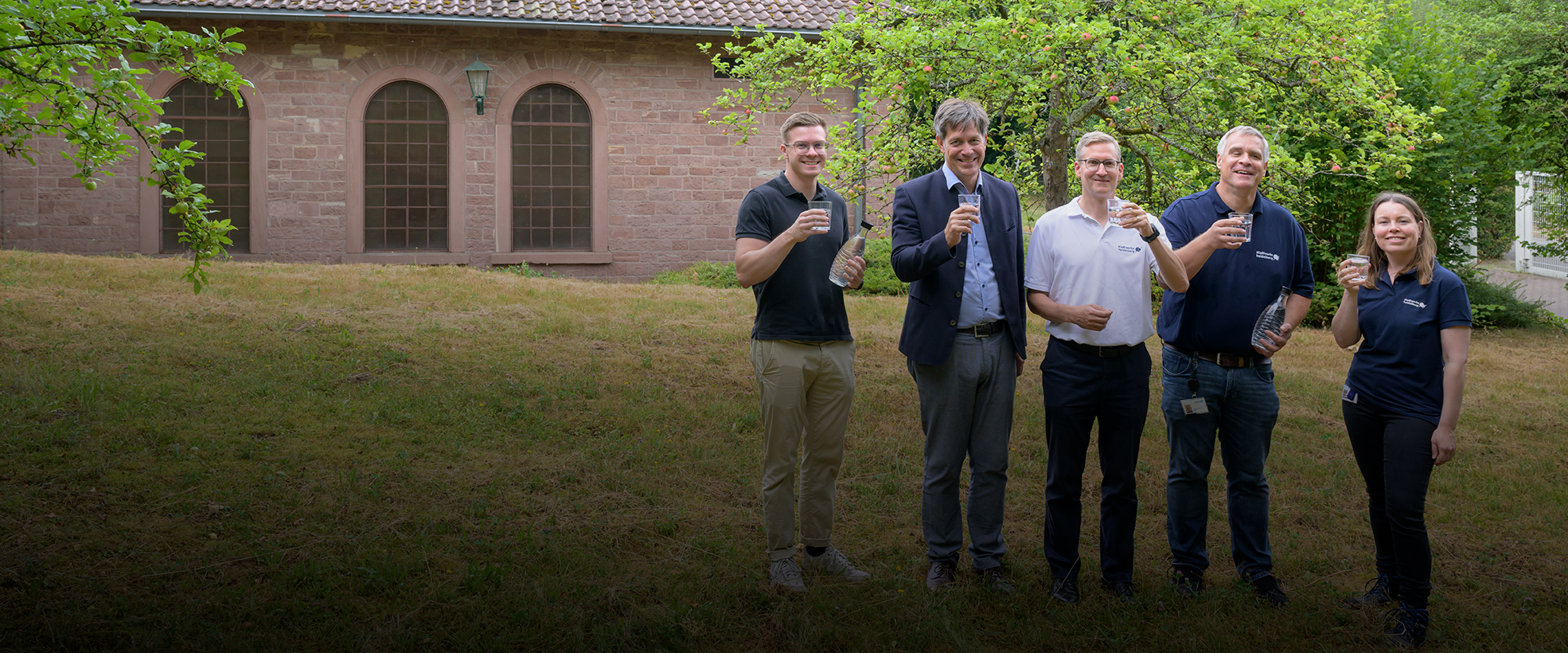 Gruppenfoto vor dem Wasserwerk. Alle prosten mit einem Glas Wasser