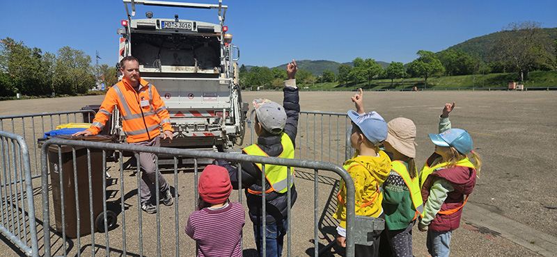 Kindergruppe stellt Fragen zu Müllauto