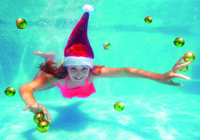 Mädchen mit Nikolausmütze schwimmt unter Wasser.