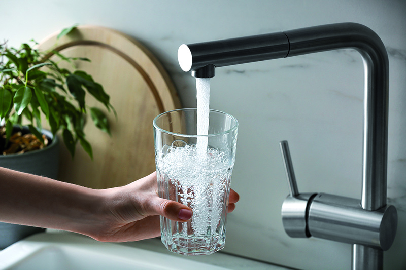 Glas wird am Wasserhahn aufgefüllt