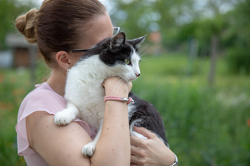 Frau in einem Garten hält Katze auf dem Arm