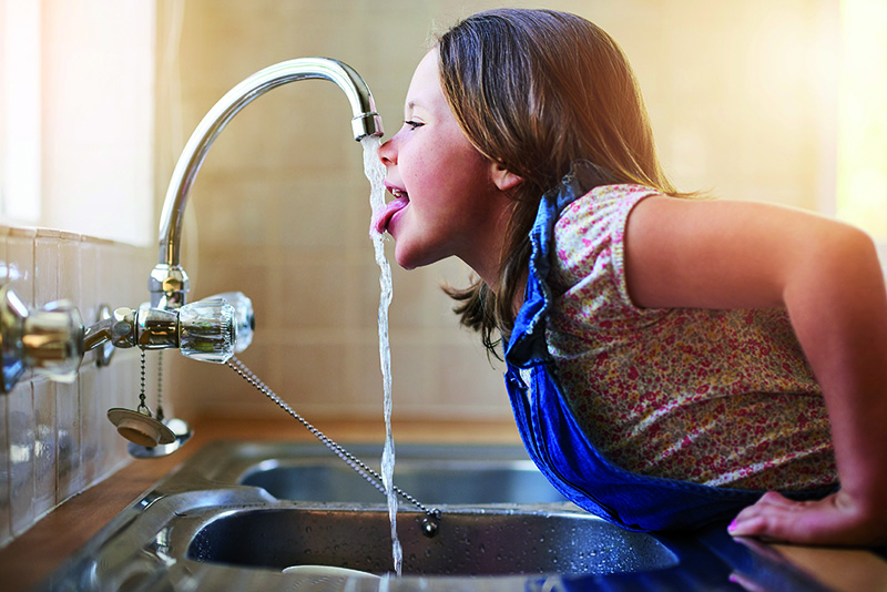 Kind trinkt aus Wasserhahn