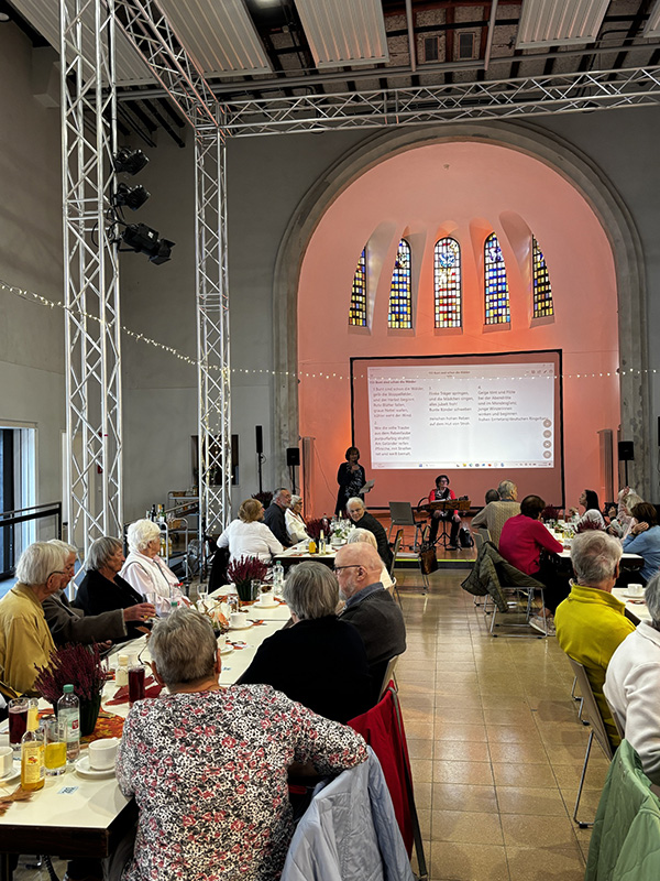 Ältere Menschen sitzen an Tischen in der Chapel