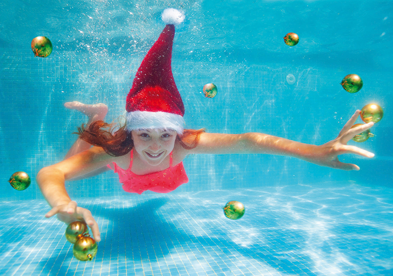 Mädchen mit Weihnachtsmütze und Christbaumkugel im Schwimmbecken