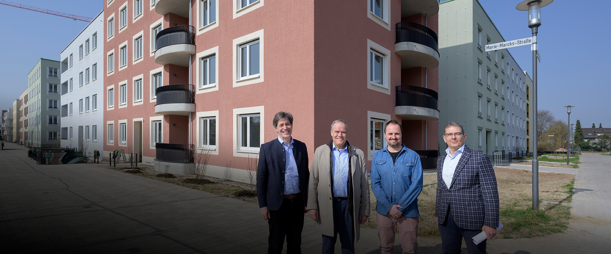 Gruppenfoto vor Neubau mit abgerundeteten Balkonen